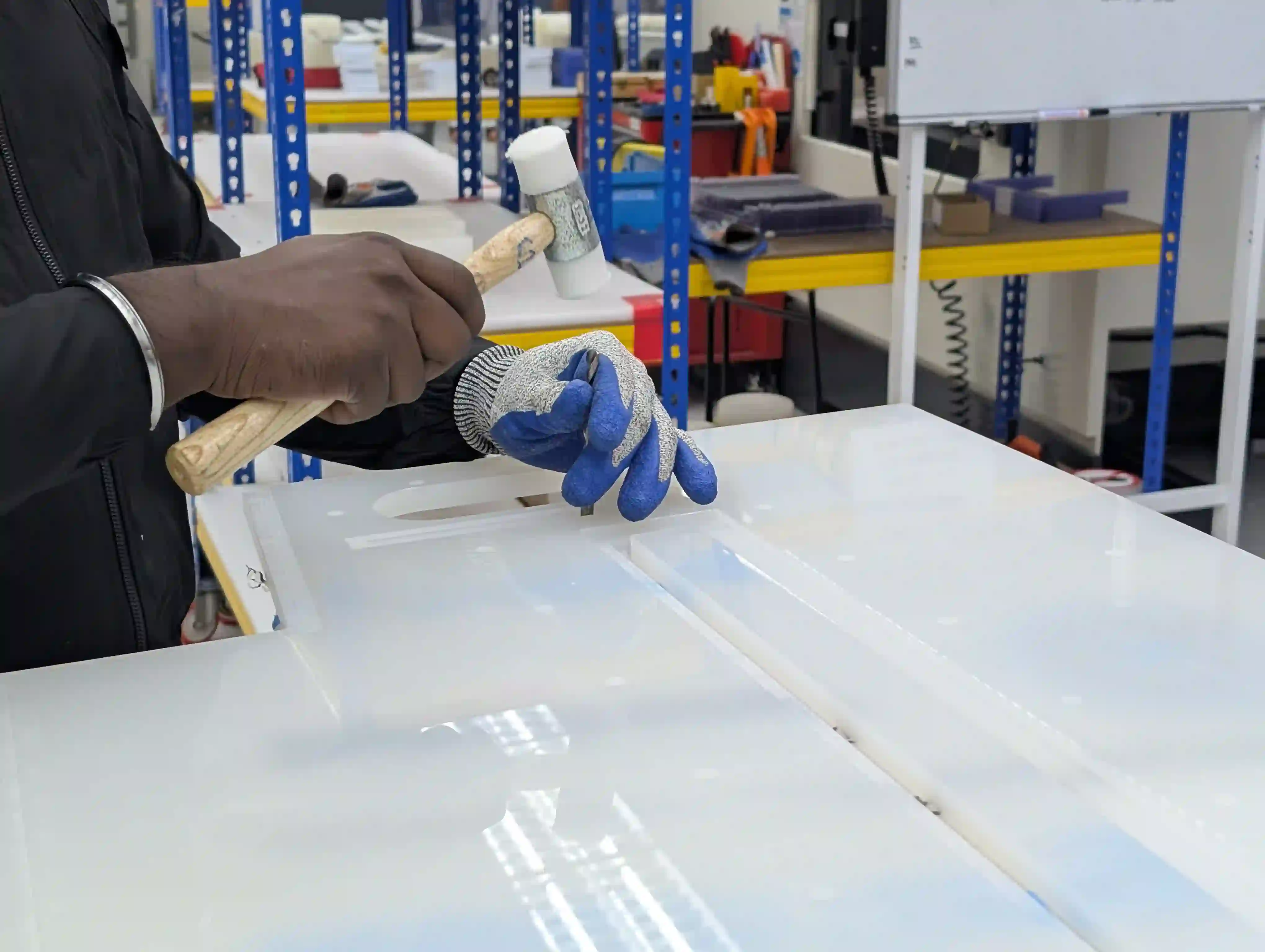 Gloved hands finishing a white workpiece in the machine shop